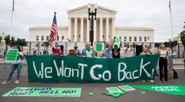 Aborträttsdemonstration utanför Högsta domstolen i USA. Aktivister håller upp en banderoll med texten: "We won't go back".  