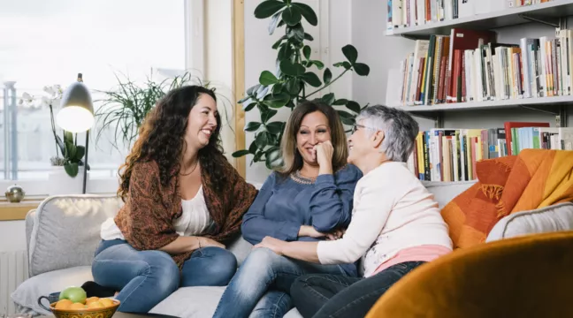Tre kvinnor sitter i en soffa och skrattar 