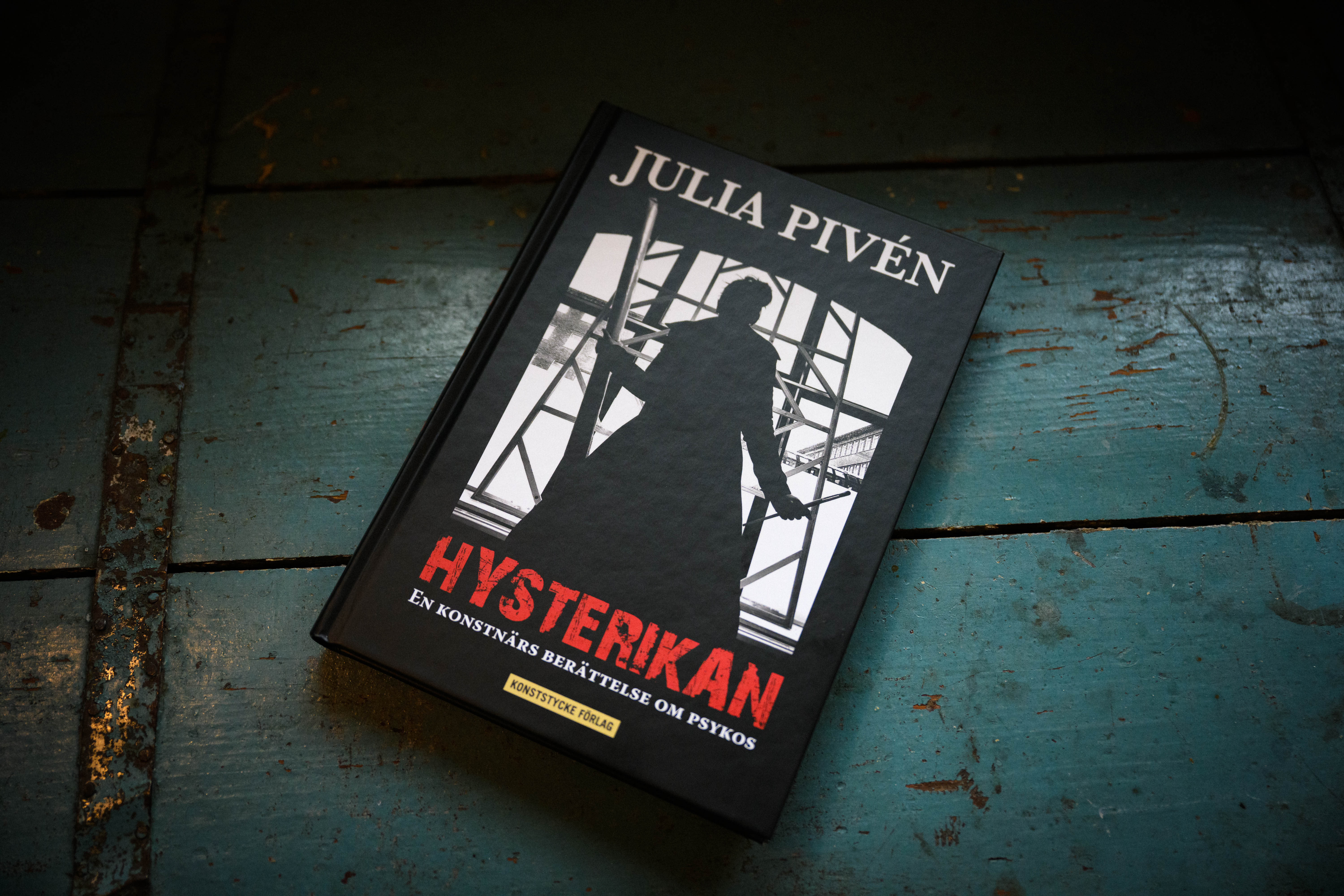 Boken Hysterikan av Julia Pivén ligger på ett blåmålat trägolv