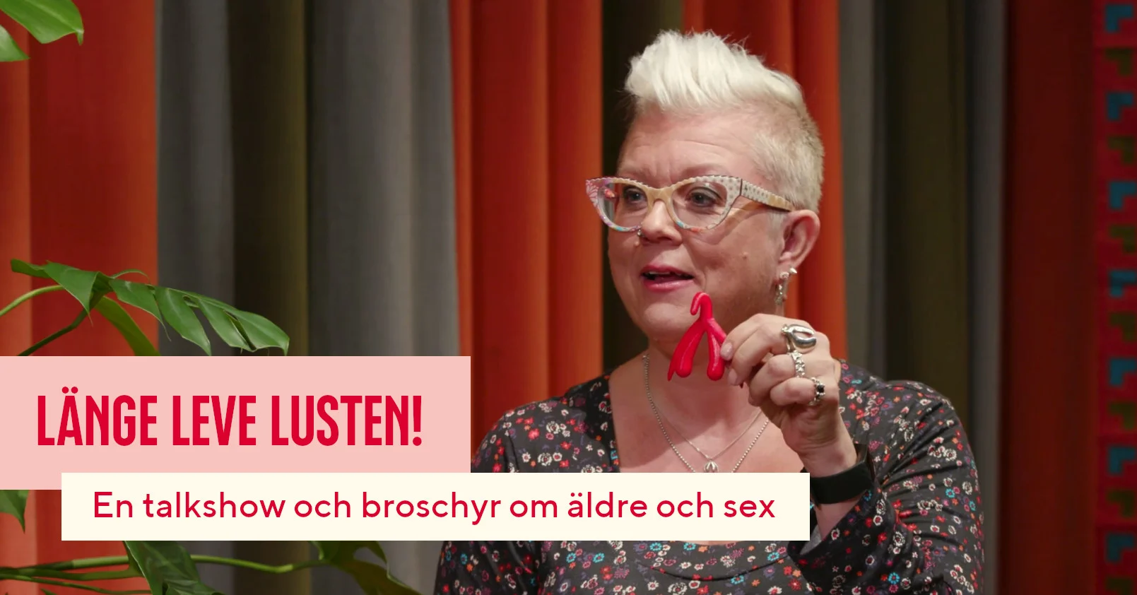 En kvinna med kort blont hår håller upp en 3D-klitorismodell. På bilden står det: Länge leve lusten i stora bokstäver och "En talkshow och broschyr om äldre och sex" i små bokstäver.