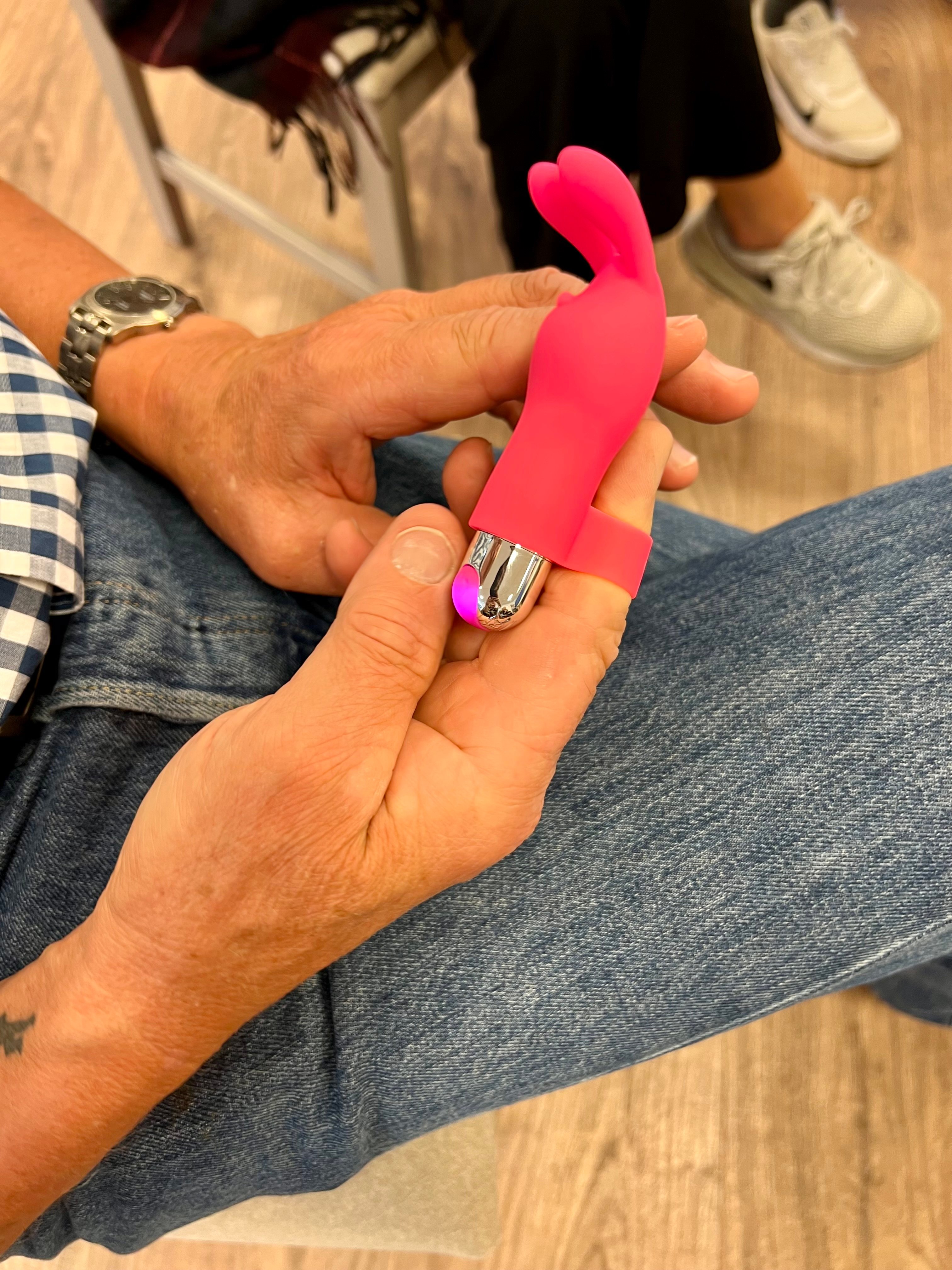 En person i jeans håller en liten rosa sexleksak i sina händer.