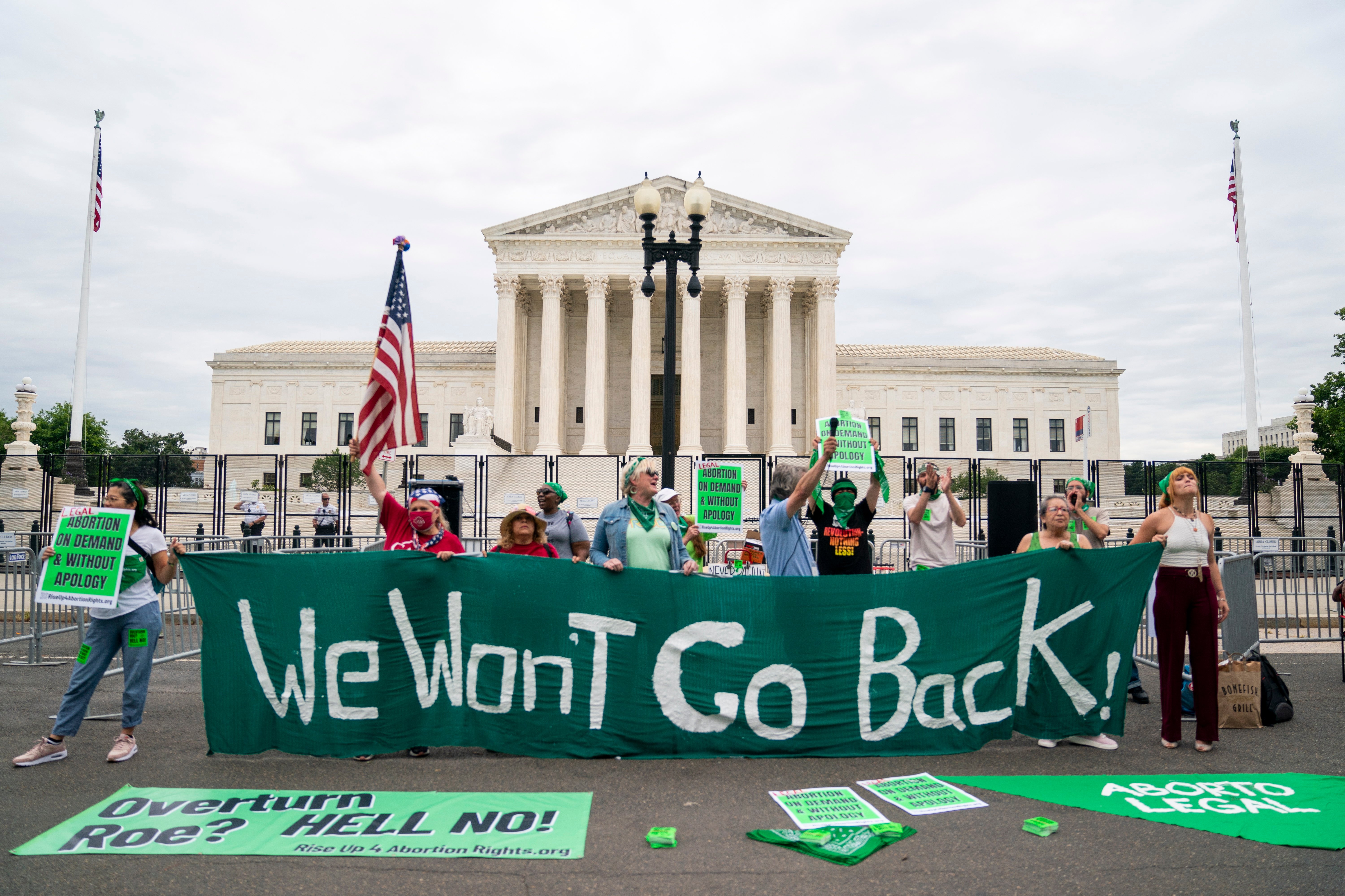 En grupp demonstranter står utanför USA:s högsta domstol och håller upp en stor grön banderoll med texten ”We Won't Go Back!”.