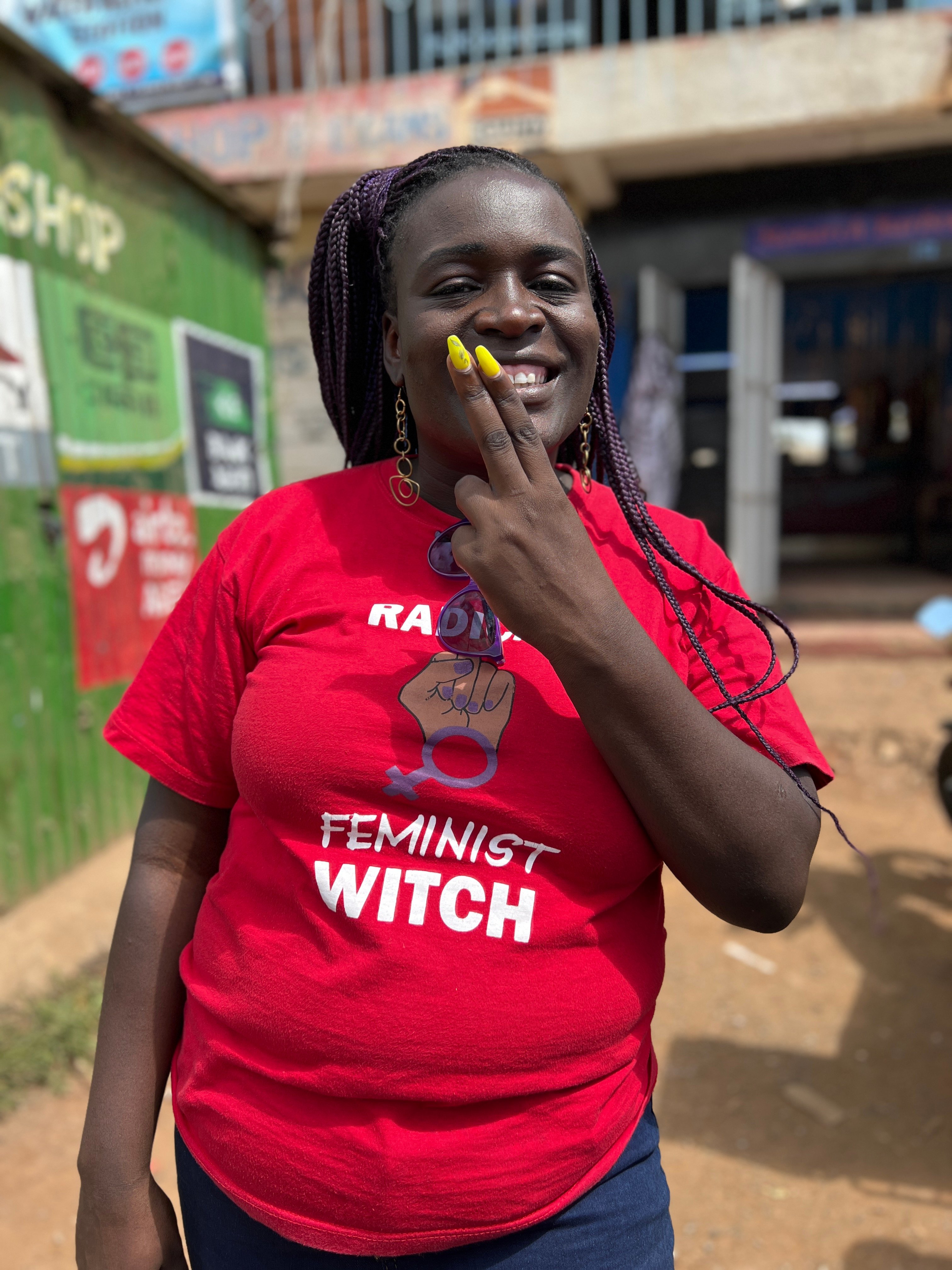 Leende person i röd t-shirt med texten RADICAL FEMINIST WITCH.