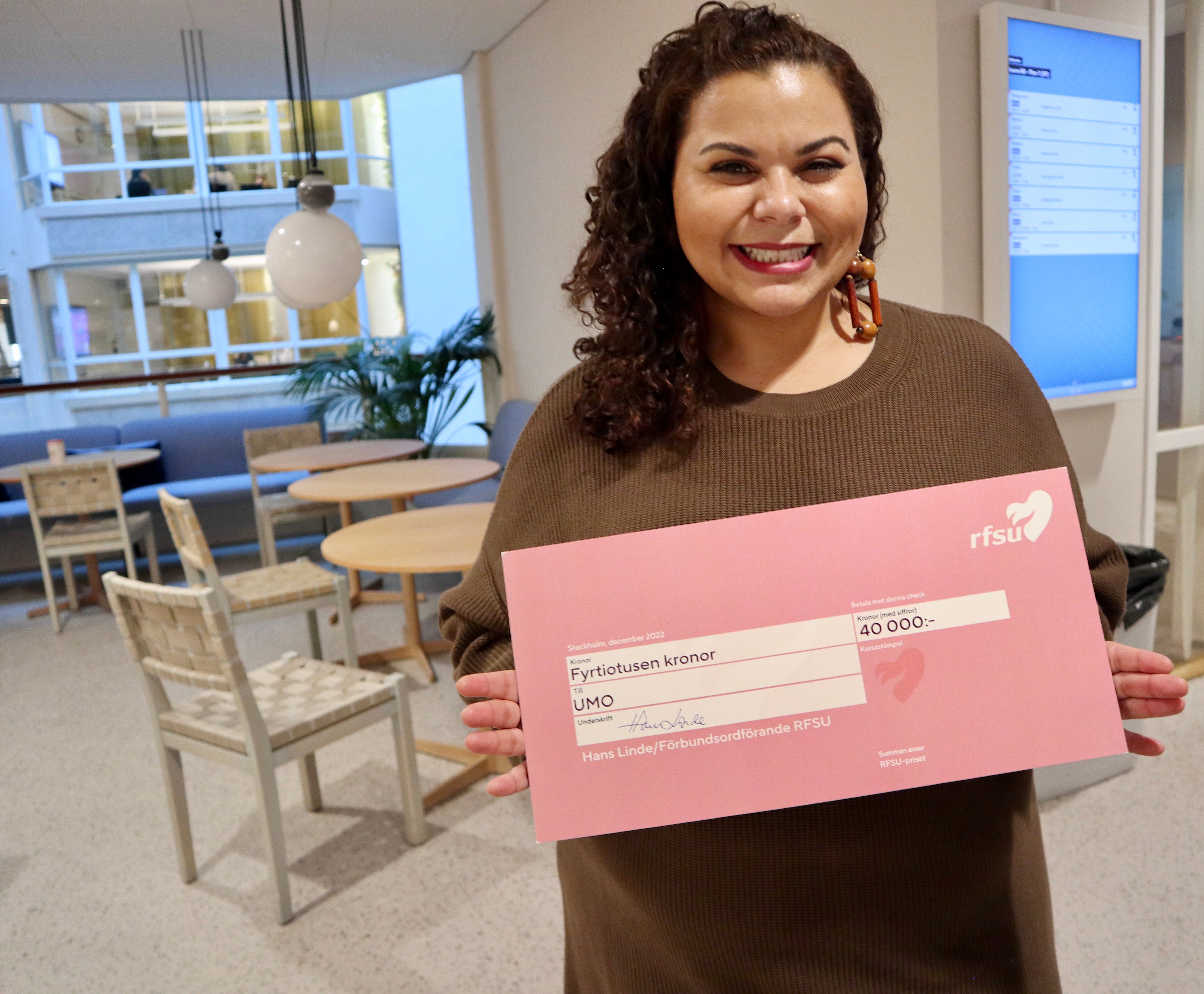 En kvinna i långt brunt hår och brun tröja poserar mot kameran med ett pris på 40000 kronor.
