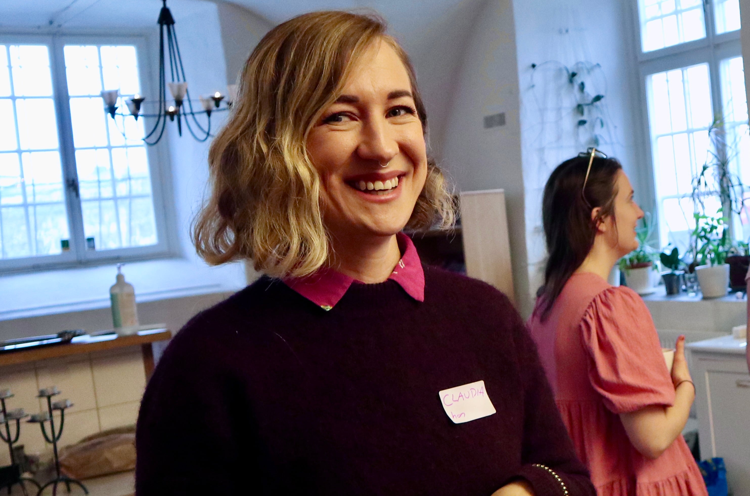 Närbild på en person som skrattar, klädd i lila tröja med namnlappen "CLAUDIA".