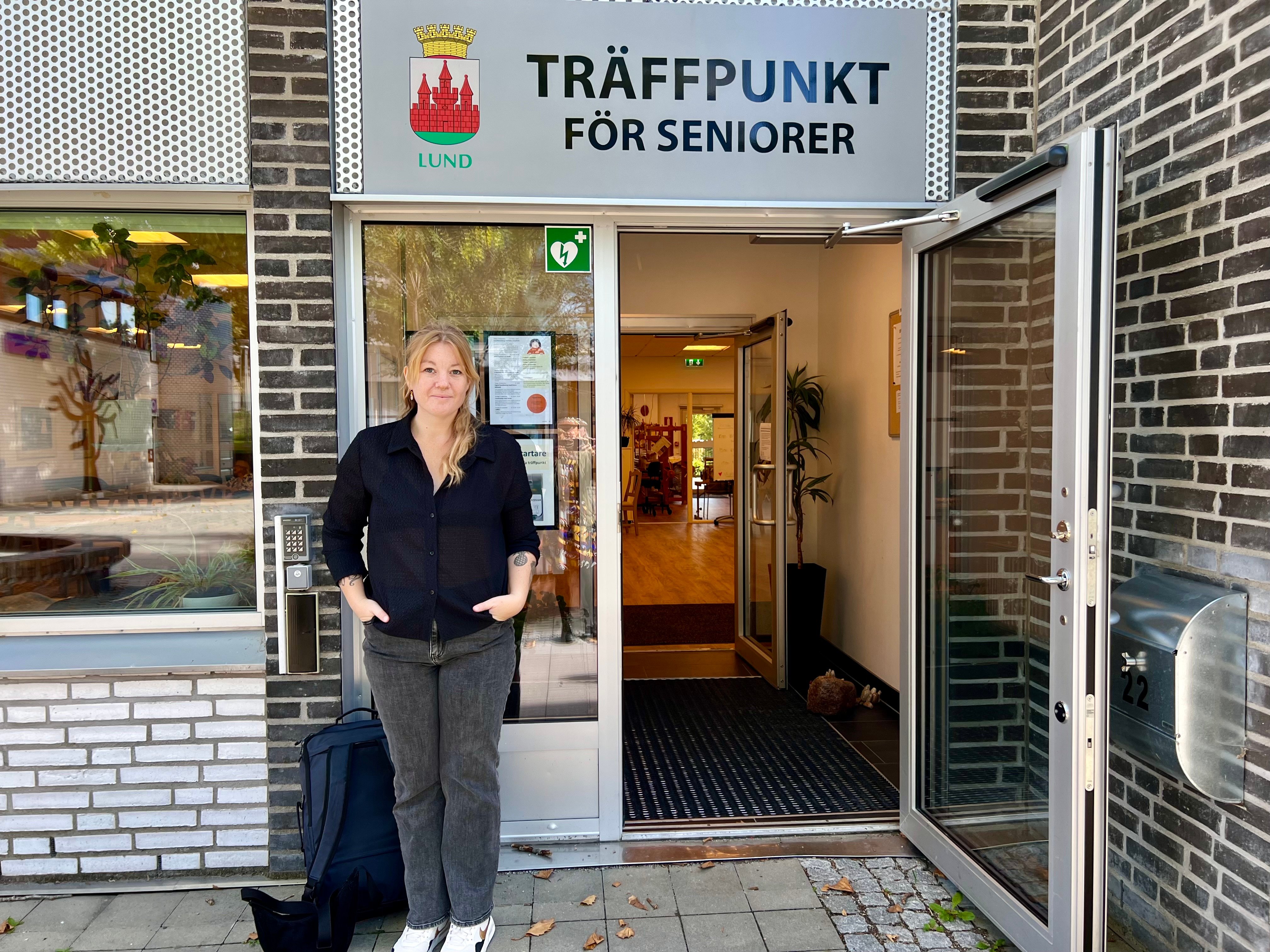 En person i mörk skjorta står framför ingången till Träffpunkt för seniorer i Lund.
