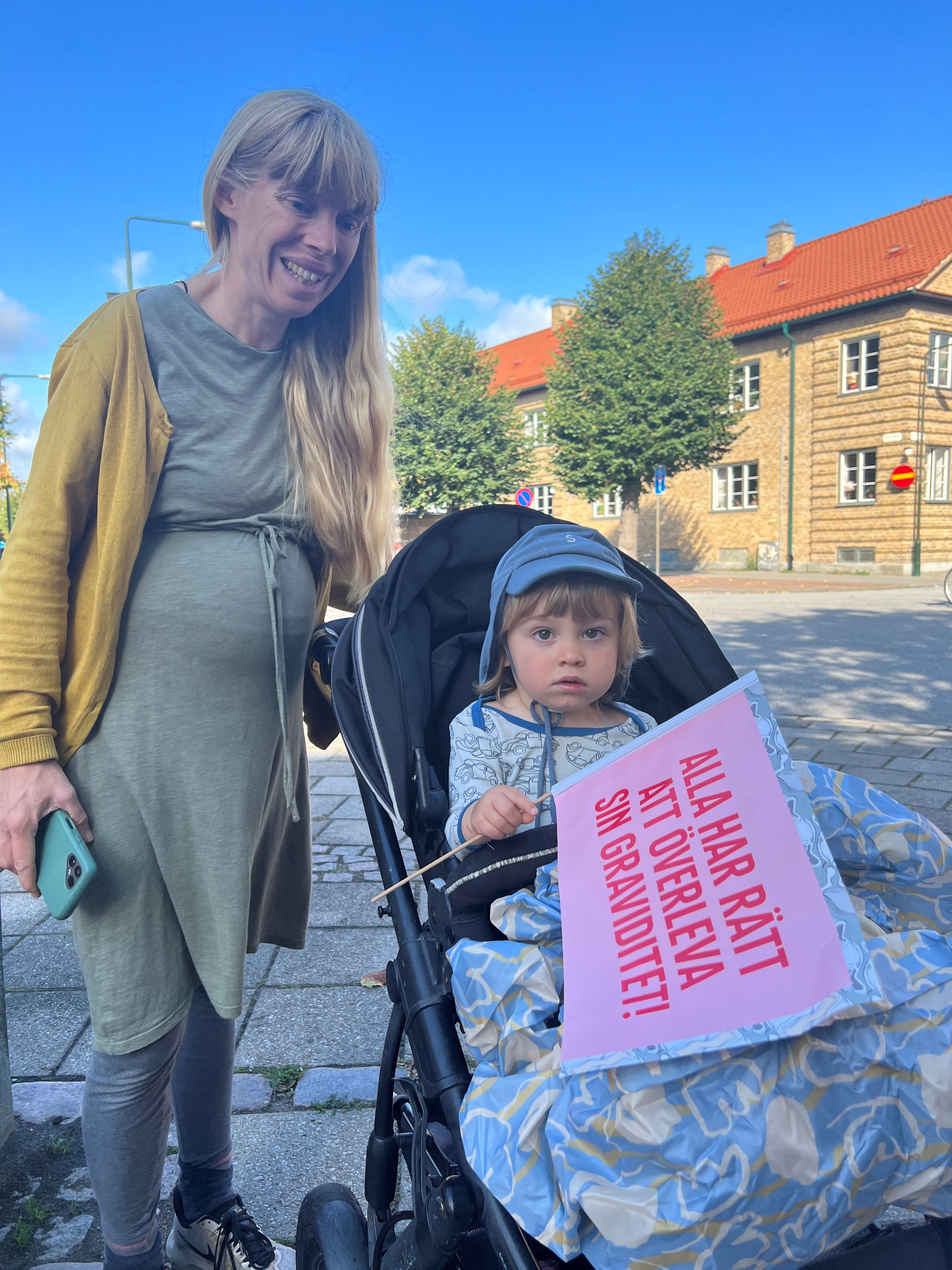 Gravid kvinna går med barn i barnvagn