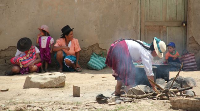En grupp av kvinnor och barn gör upp en eld på bolivianska landsbygden 