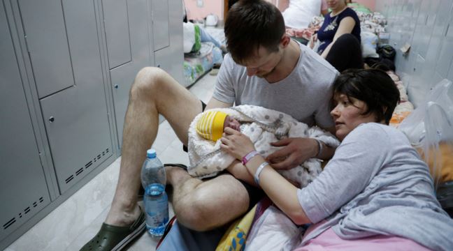 Ett par med ett nyfött barn i ett skyddsrum i Kyiv, Ukraina.  