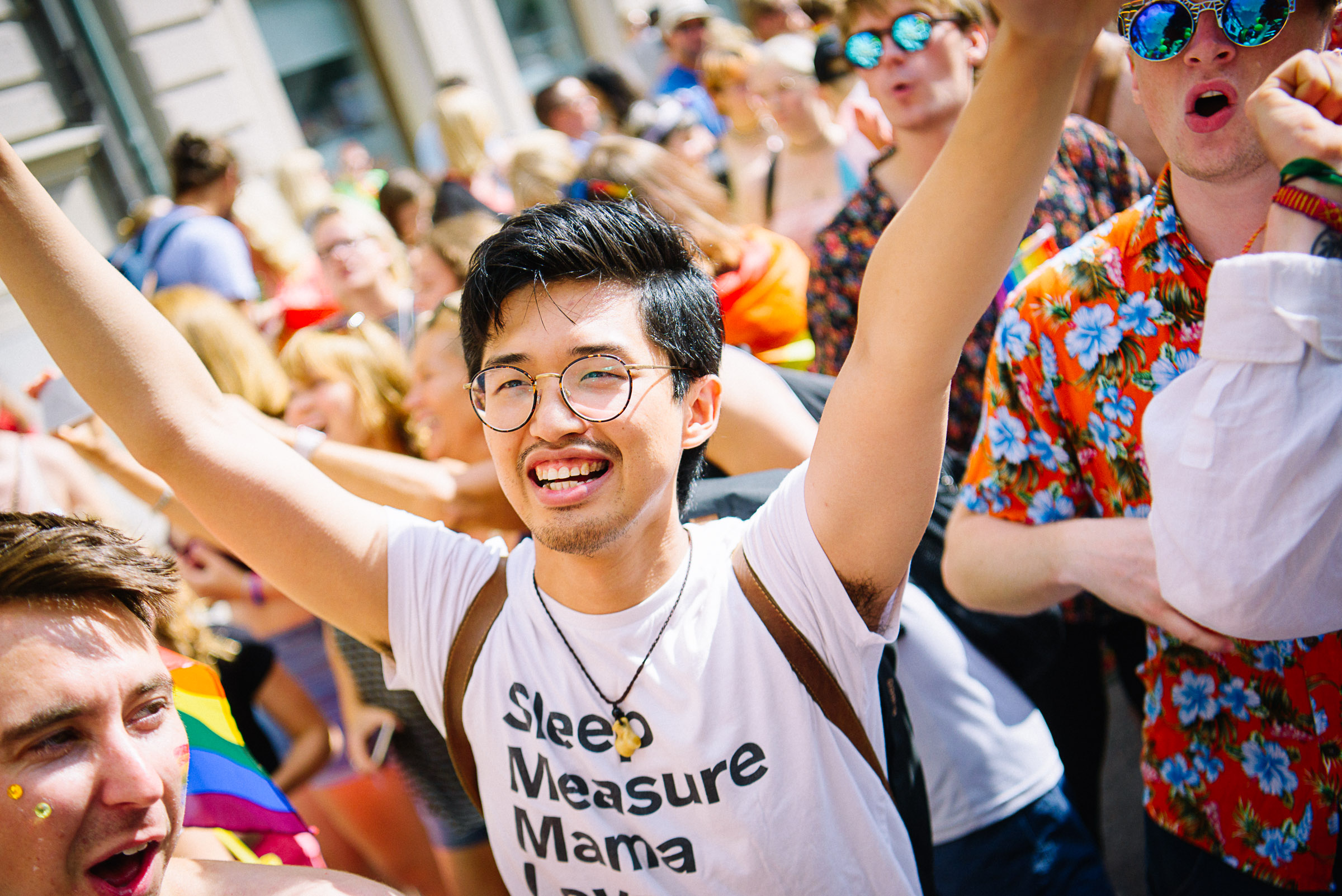 Glad person med armarna i luften under en Prideparad 