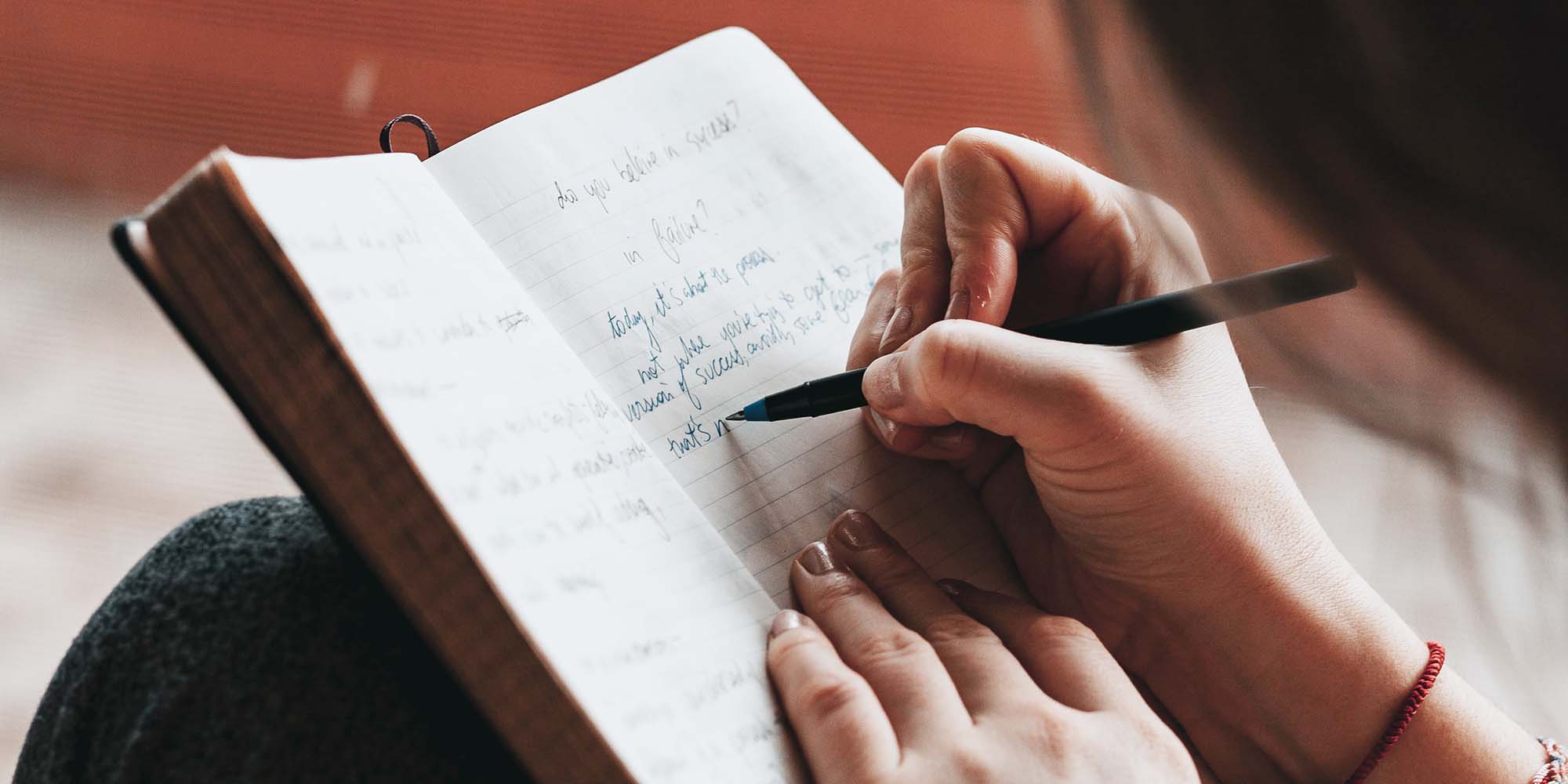 Händer som antecknar i ett skrivblock, foto 