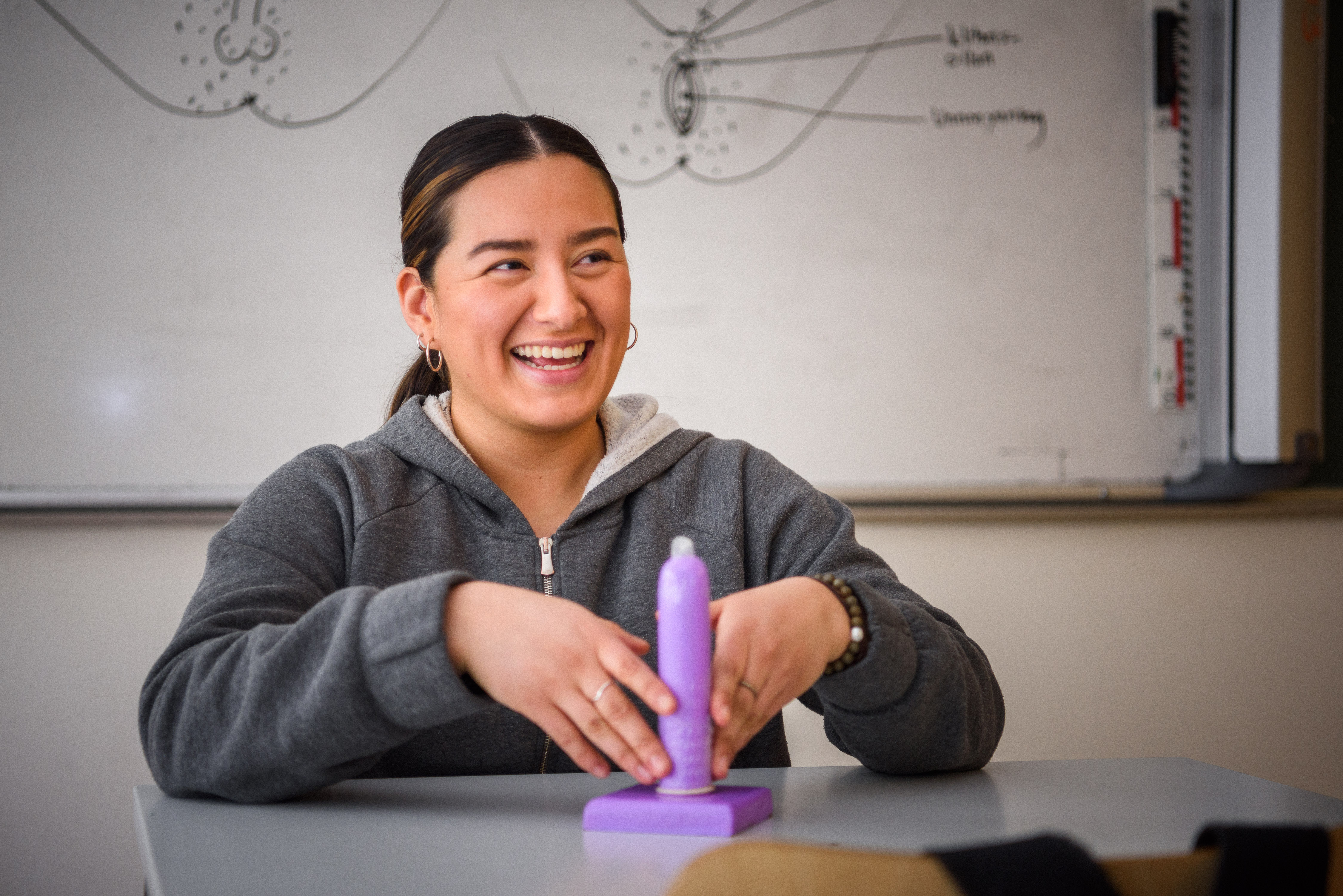 Lärare eller RFSU-informatör i ett klassrum visar hur man trär på en kondom 