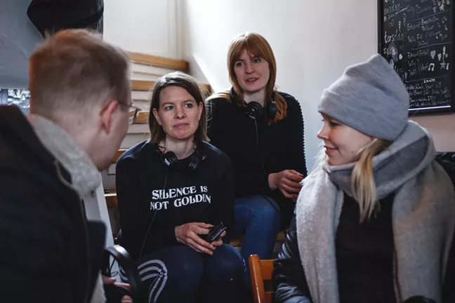 Projektledarna för Hemma sitter i en trappa och pratar med filmproducenterna.. 