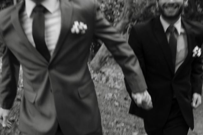 Två män i kostym håller varandra i handen. 