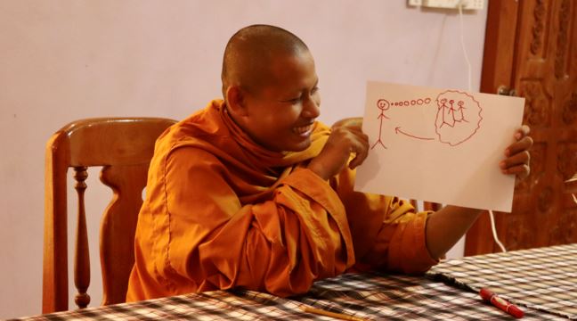 Glad munk visar upp en teckning med streckgubbar. 