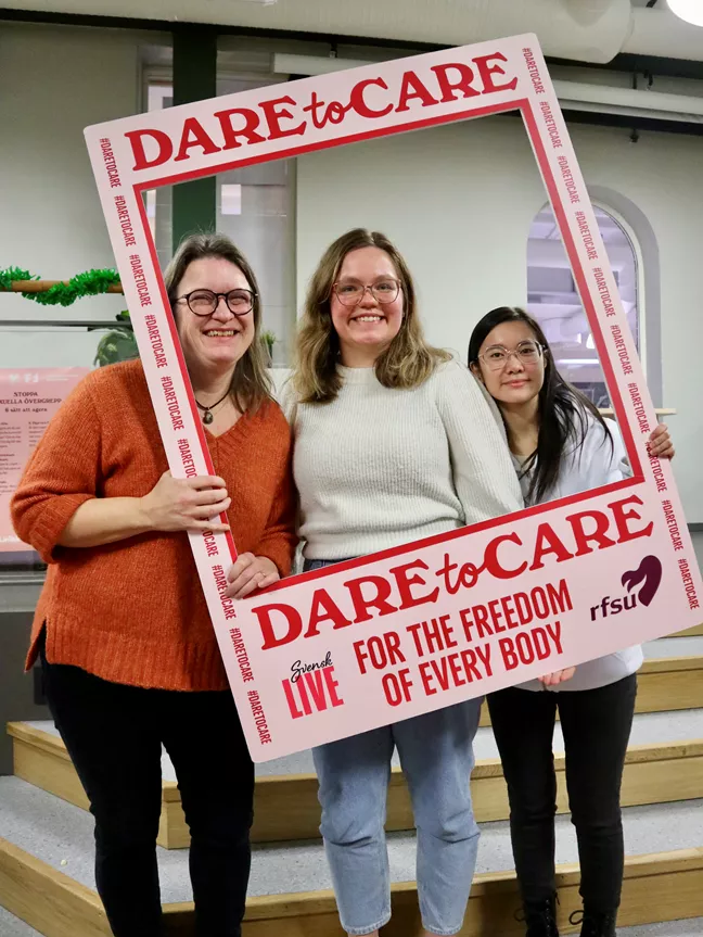 Tre personer med långt hår och glasögon kikar ut ur en ram som det står Dare to Care på.  