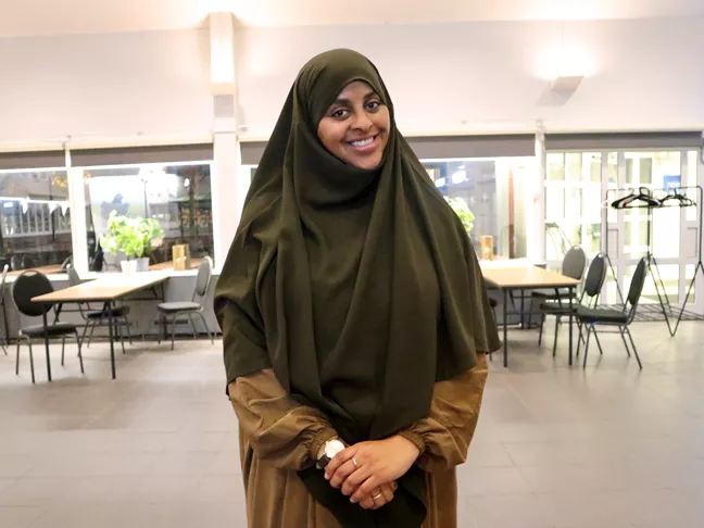 Person i slöja ler och tittar in i kameran.  