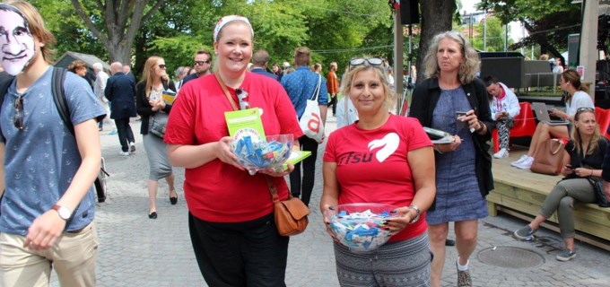 Två personer i rfsu-tröjor håller fram skålar med kondomer. 