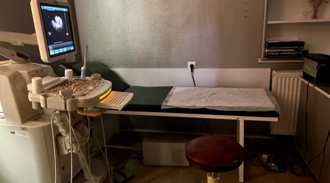 Bild på ett undersökningsrum med en ultraljudsmaskin bredvid en brits. 