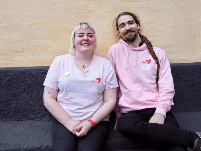 Två personer i rfsu-tröjor sitter bredvid varandra och ser glada ut. 