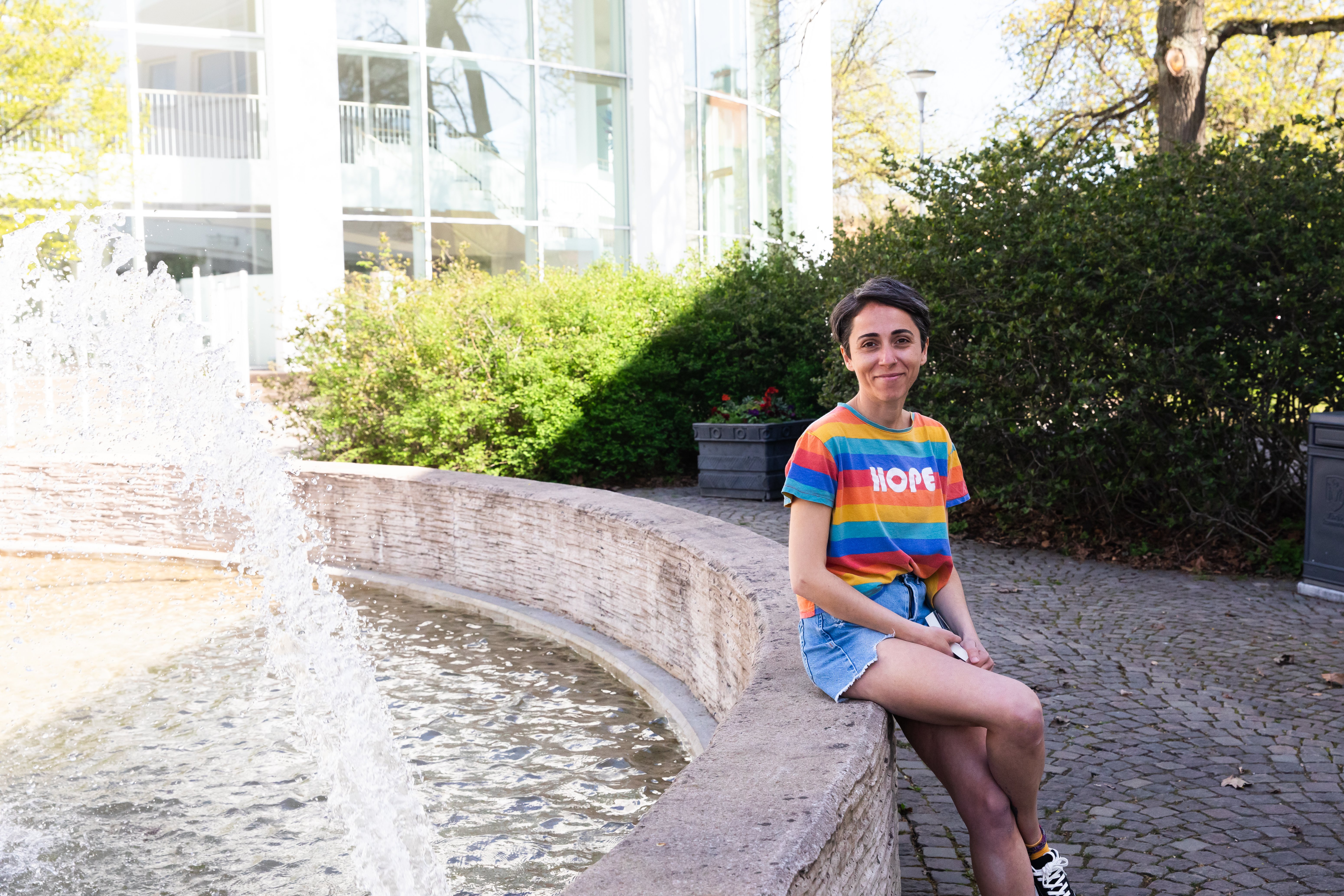 Ceren sitter på kanten av en fontän. 