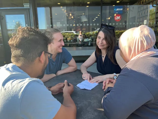 Fyra personer sitter vid ett bord och samtalar med varandra. 