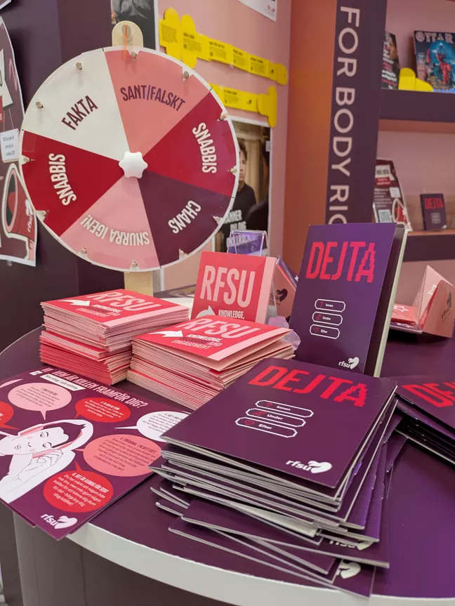 Några broschyrer och ett hjul man kan snurra på står i en mässtmonter. 