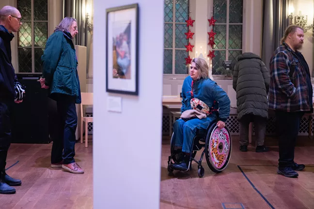 En person i rullstol med färgglada hjul tittar på utställningen. 