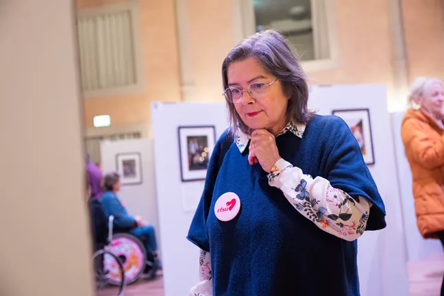 En person med en RFSU-knapp på bröstet ser ut att ta del av utställningen. Hon har handen i hakan och ser fundersam eller upptagen ut. 