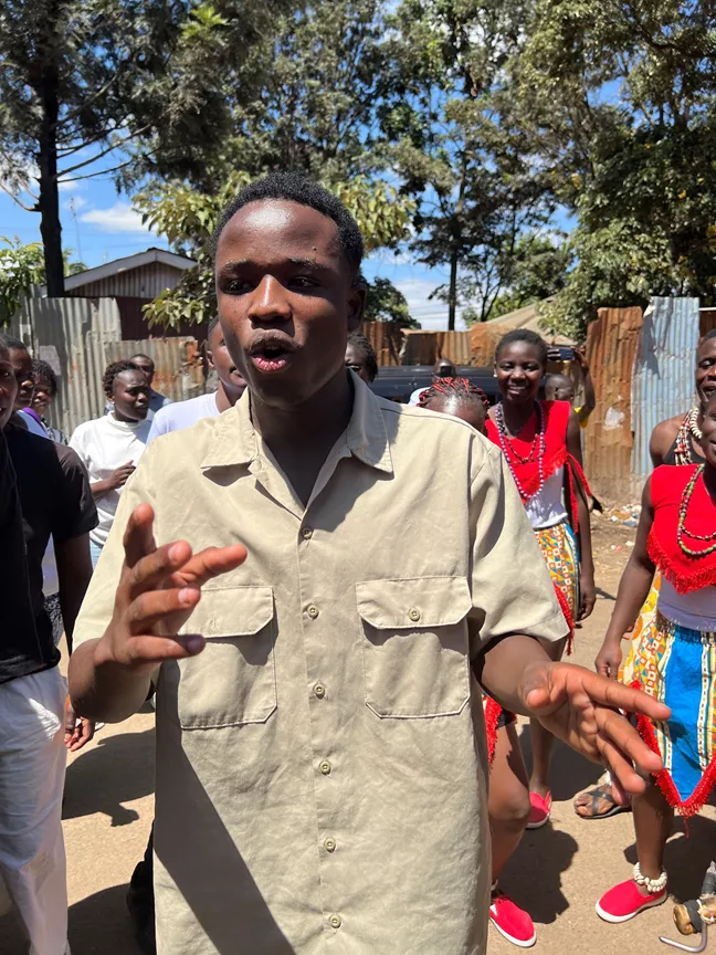 En ung man i beige skjorta dansar utomhus. 