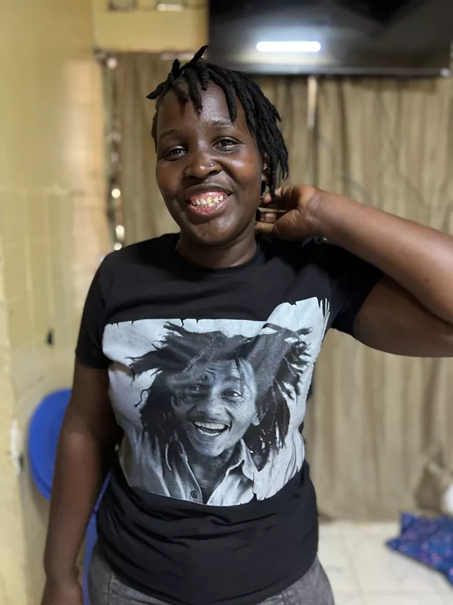 En person med Bob Marley-tröja, ler och ser lite busig ut. 