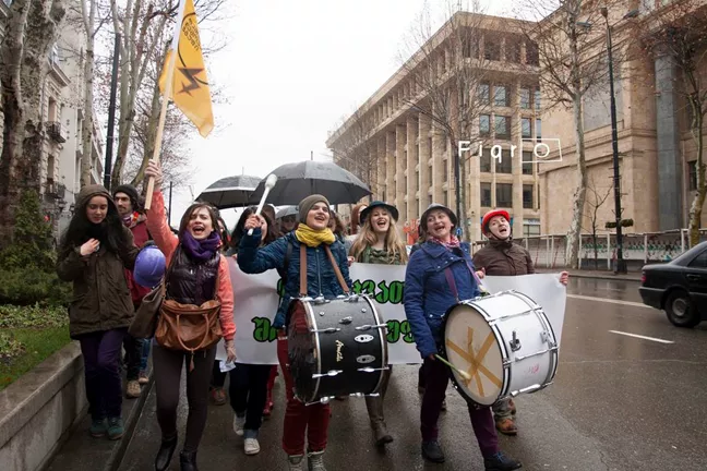 Ett demonstrationståg med trummor och paraplyer. 