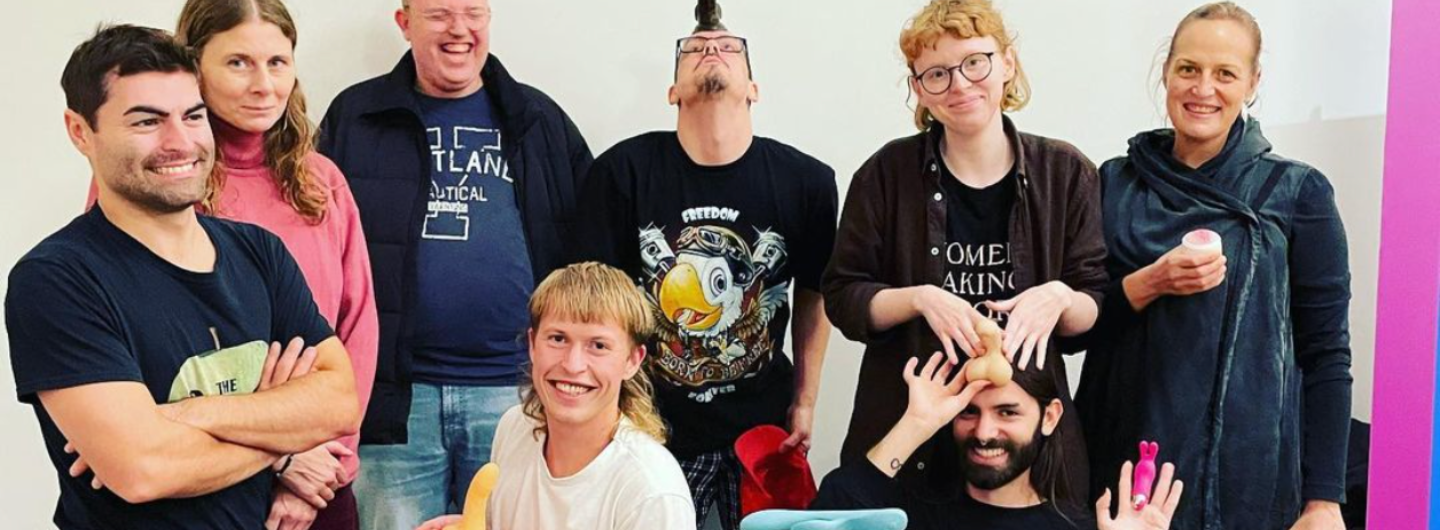 tta personer från 'Sex för Alla' deltar i en cafékväll där de tar en gruppbild. På gruppbilden visar upp sexleksaker. 