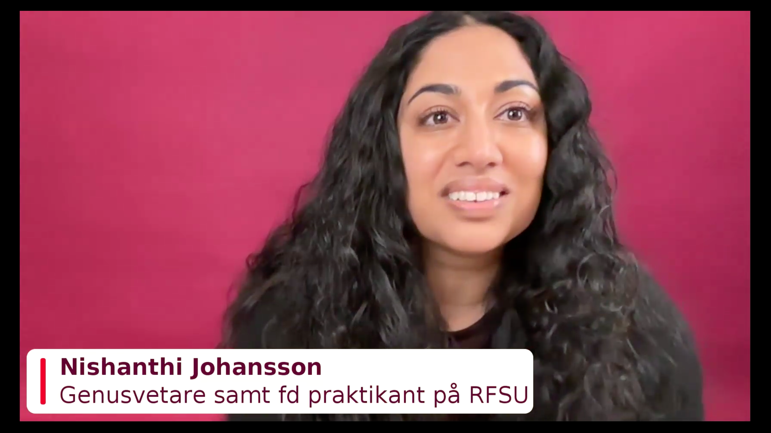 En kvinna med med långt svart hår framför en mörkrosa bakgrund med en namskylt i hörnet.