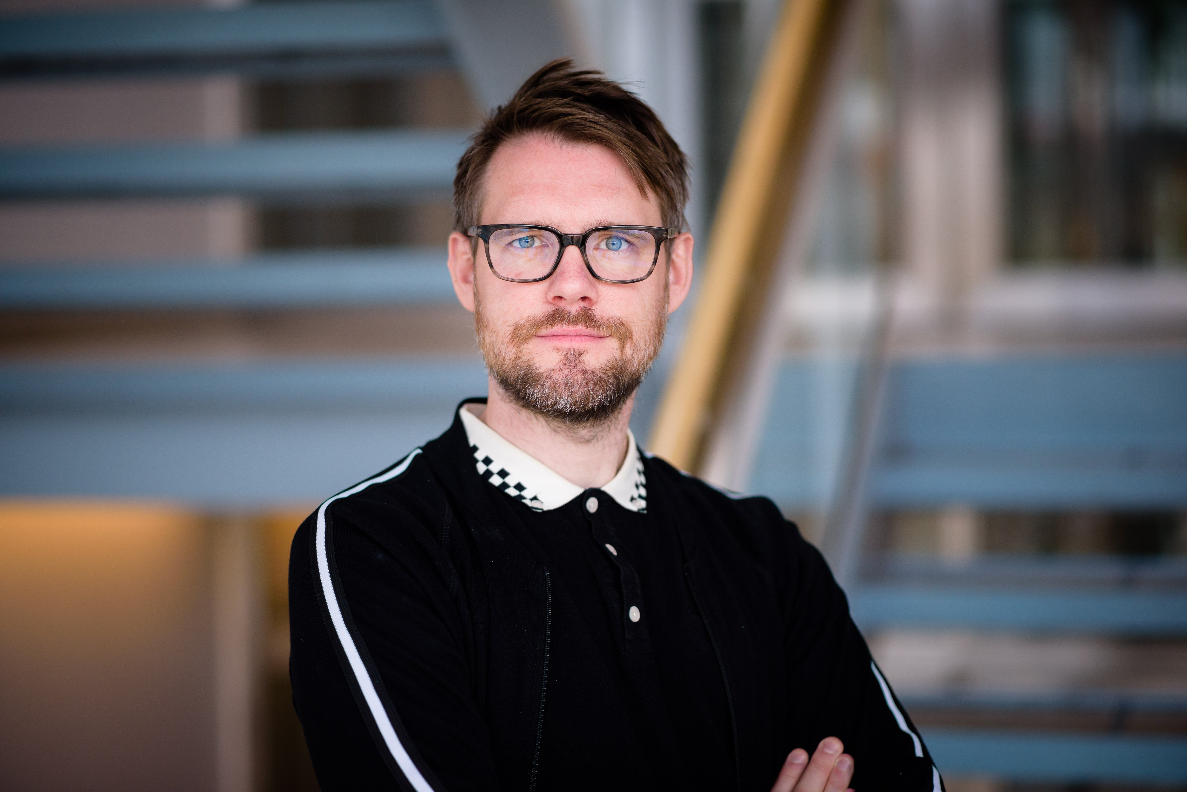Porträtt på man med skägg och glasögon.