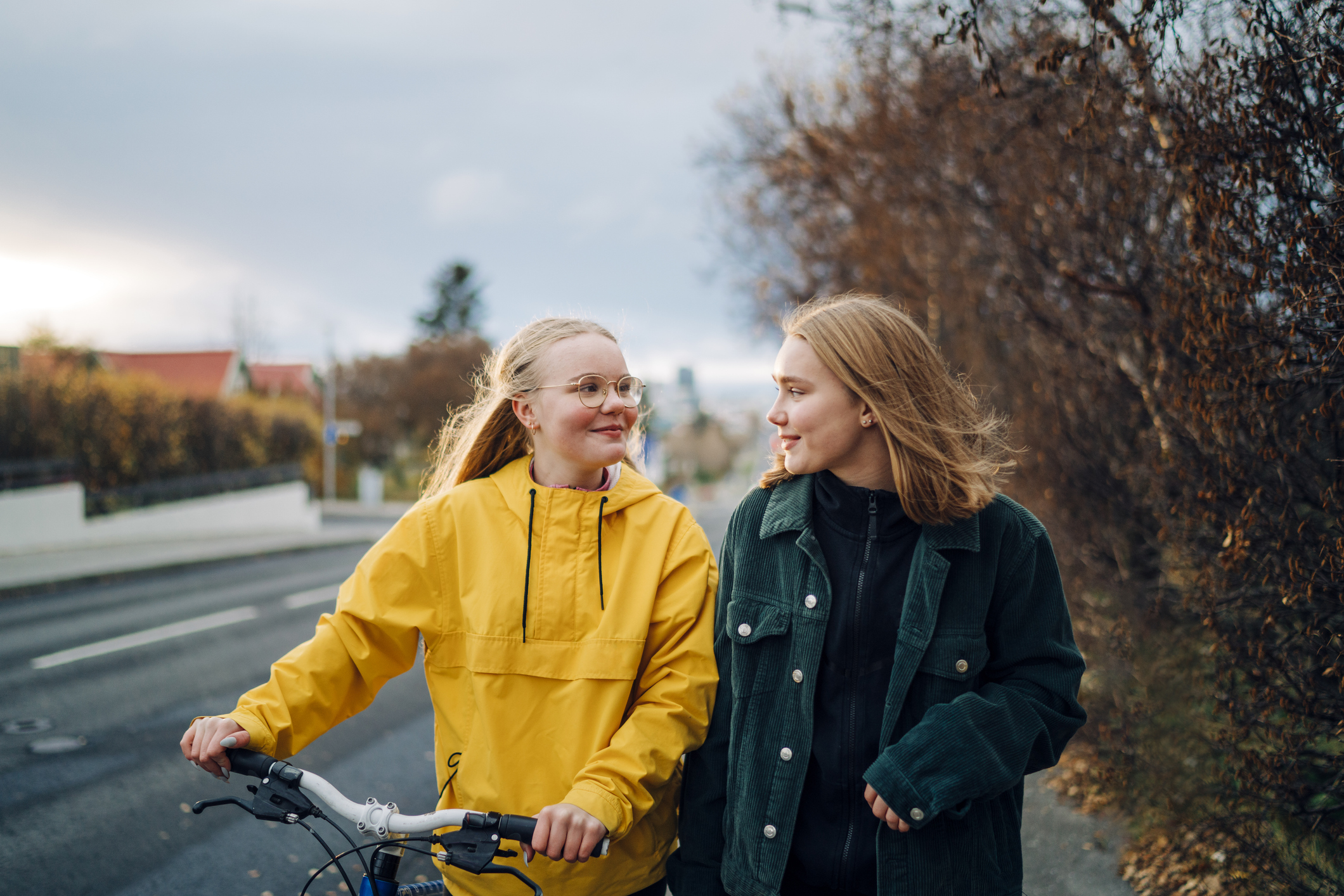 Två unga tjejer går på gatan och tittar på varandra.