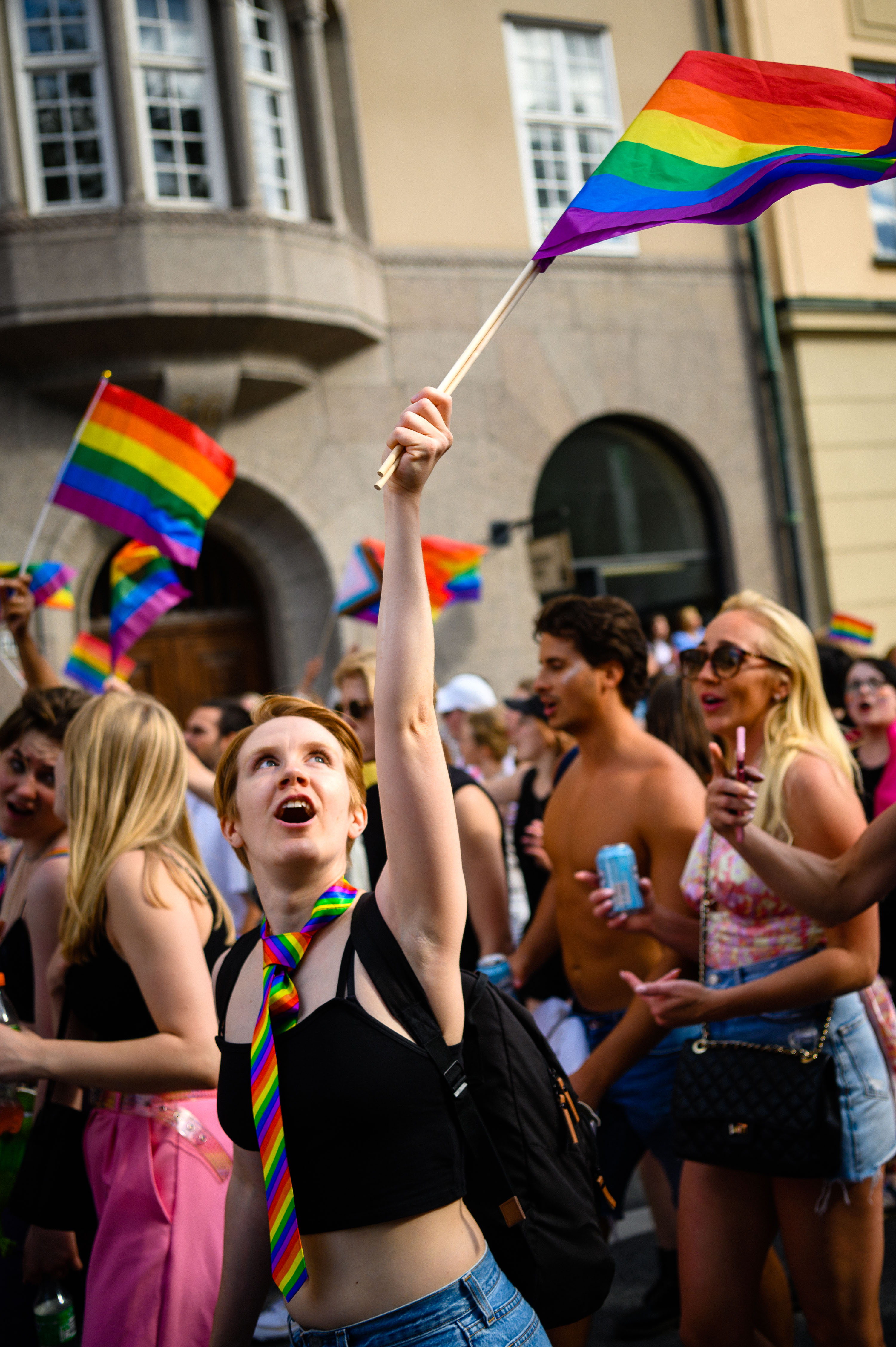Deltagare på Stockholm Pride viftar med prideflaggor