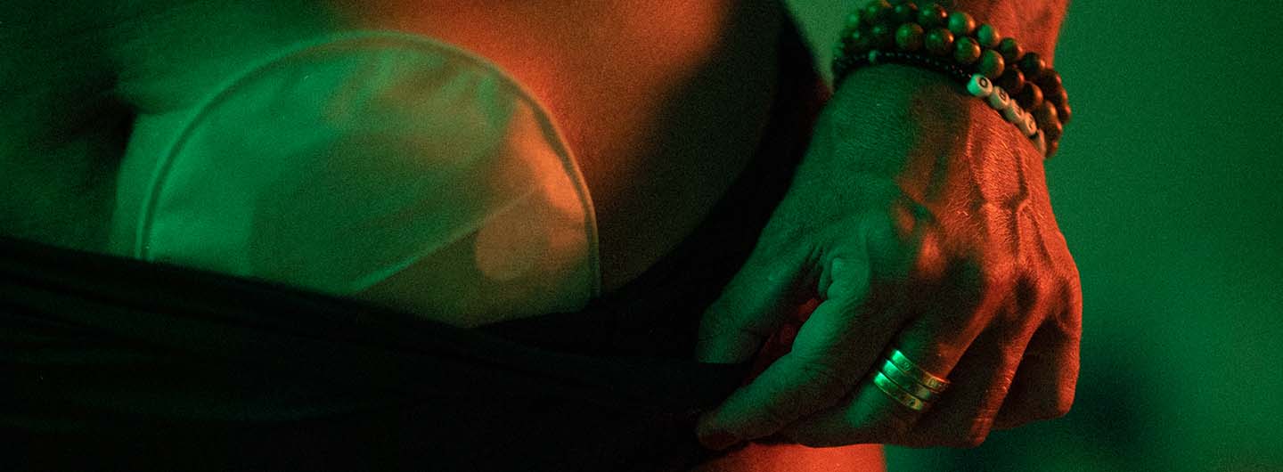 En hand med armband och silverringar håller i en troskant. Ovanför troskanten syns en stomipåse. 