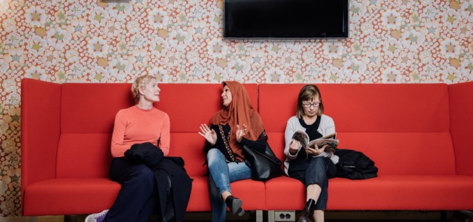 Tre kvinnor sitter i en soffa i ett väntrum. 