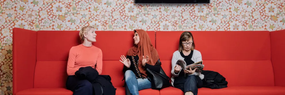 Tre kvinnor sitter i en soffa i ett väntrum. 